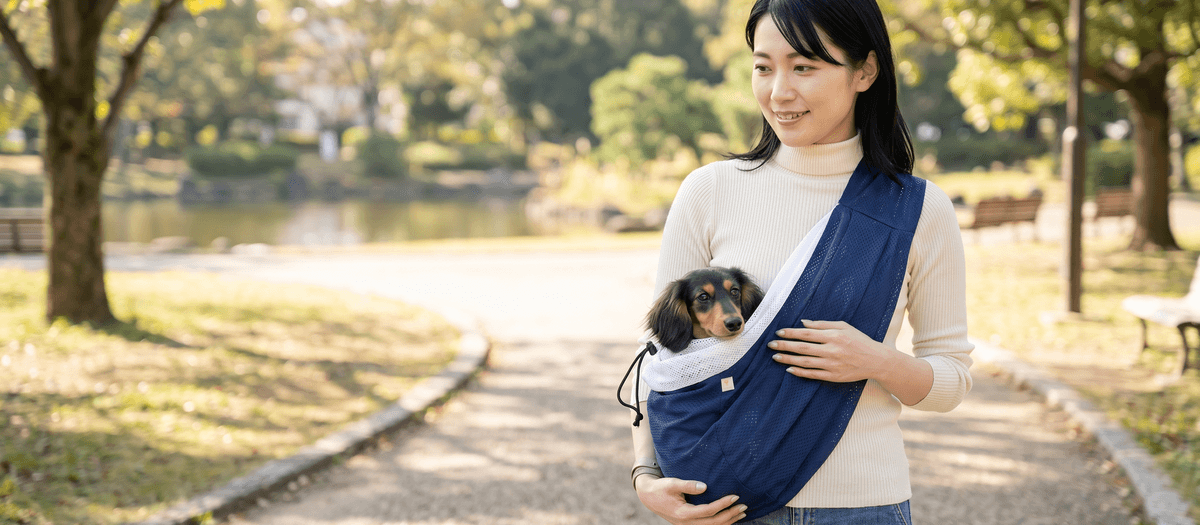 ドッグスリングで犬または猫を抱っこし安心した表情を見せるオーナー